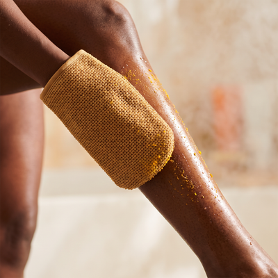 Corvae Exfoliating Glow Mitt in use on glowing skin